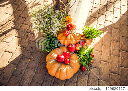 Wedding arch for off-site wedding ceremony, decorated in autumn theme with pumpkins 129620327