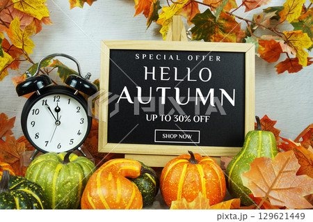 Autumn Sale 30% text with alarm clock and maple leaf decoration on wooden background Autumn Sale 30% text with alarm clock and maple leaf decoration on wooden background 129621449