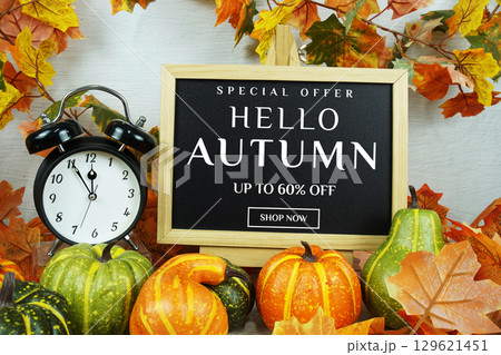 Autumn Sale 60% text with alarm clock and maple leaf decoration on wooden background 129621451