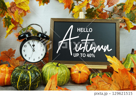 Autumn Sale 40% text with alarm clock and maple leaf decoration on wooden background Autumn Sale 40% text with alarm clock and maple leaf decoration on wooden background 129621515