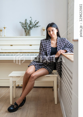 Woman sitting on bench in front of piano, portrait 129622081