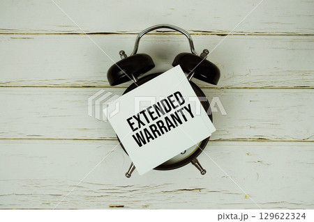Extended Warranty text message on paper with alarm clock on wooden background Extended Warranty text message on paper with alarm clock on wooden background 129622324