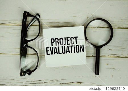 Project Evaluation text message on paper with magnifying glass and eyeglasses on wooden background 129622340