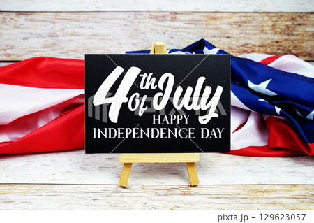 Happy 4th Of July Independence Day text on blackboard with USA flag American holiday background 129623057