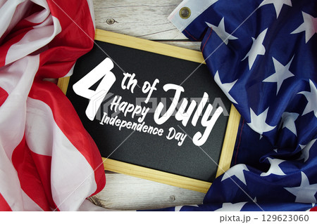 Happy 4th Of July Independence Day text on blackboard with USA flag American holiday background Happy 4th Of July Independence Day text on blackboard with USA flag American holiday background 129623060
