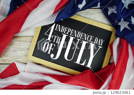 Happy 4th Of July Independence Day text on blackboard with USA flag American holiday background 129623061