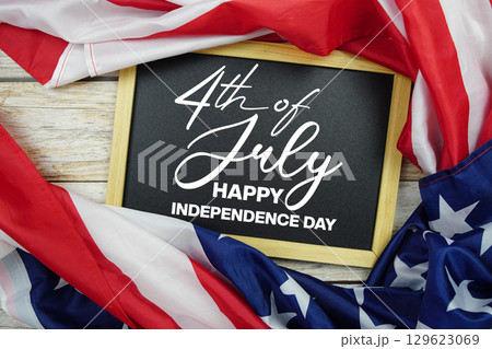 Happy 4th Of July Independence Day text on blackboard with USA flag American holiday background 129623069