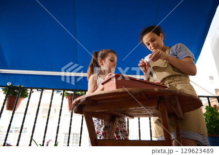 Mother and Daughter Gardening Together on a Sunny Balcony Mother and Daughter Gardening Together on a Sunny Balcony 129623489