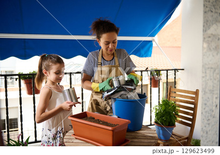 Mother and Daughter Gardening Together on a Cozy Balcony 129623499