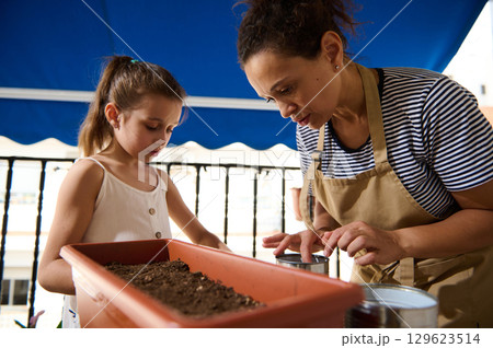 Mother and Child Enjoy Gardening Together on a Sunlit Balcony Mother and Child Enjoy Gardening Together on a Sunlit Balcony 129623514