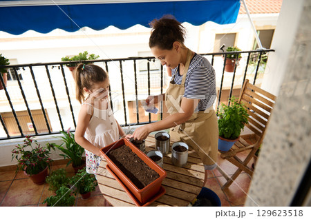 Mother and Daughter Plant Seeds Together on a Cozy Balcony 129623518