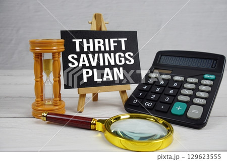 TSP Thrift Savings Plan text with magnifying glass and calculator on wooden background TSP Thrift Savings Plan text with magnifying glass and calculator on wooden background 129623555