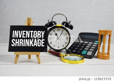 Inventory Shrinkage text with magnifying glass and calculator on wooden background 129623559