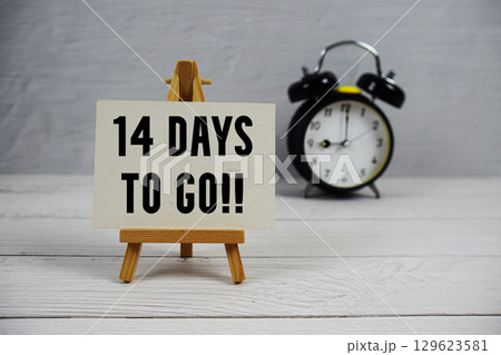 14 Days To Go! text with easel and alarm clock on wooden background 129623581