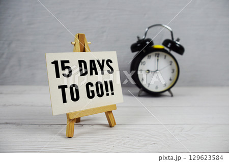 15 Days To Go! text with easel and alarm clock on wooden background 129623584