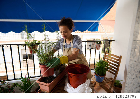 Woman Enjoying Gardening on Her Balcony with Flower Pots and Plants 129623708