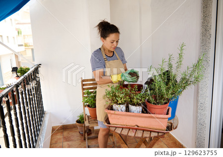 Woman Tending to Plants on a Balcony: Gardening and Nature Hobby Woman Tending to Plants on a Balcony: Gardening and Nature Hobby 129623755