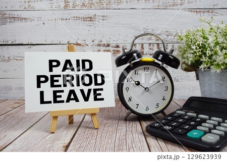 Paid Period Leave text with alarm clock and calculator on wooden background 129623939