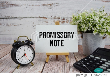 Promissory Note text with alarm clock and calculator on wooden background 129623946