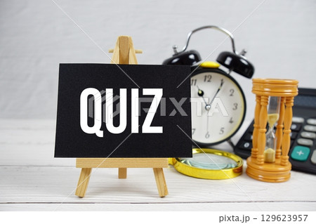 Quiz text with magnifying glass and calculator on wooden background 129623957