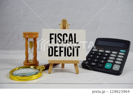 Fiscal Deficit text with magnifying glass and calculator on wooden background Fiscal Deficit text with magnifying glass and calculator on wooden background 129623964