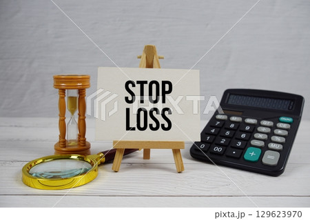 Stop Loss text with magnifying glass and calculator on wooden background 129623970
