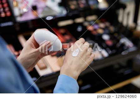 A woman is carefully applying a nourishing cream to her hand 129624060