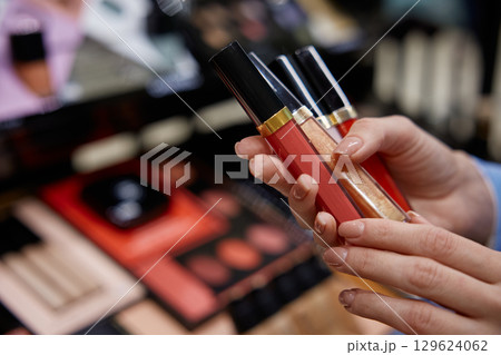 A woman in a blue jacket choosing cosmetics in a store touching the merchandise 129624062