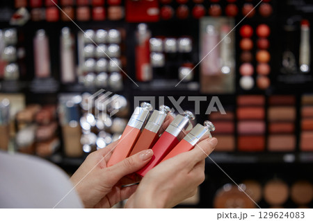 A woman is carefully holding a beautiful row of colorful lipsticks in her hands A woman is carefully holding a beautiful row of colorful lipsticks in her hands 129624083