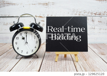 Real-time Bidding text with easel and alarm clock on wooden background 129625120