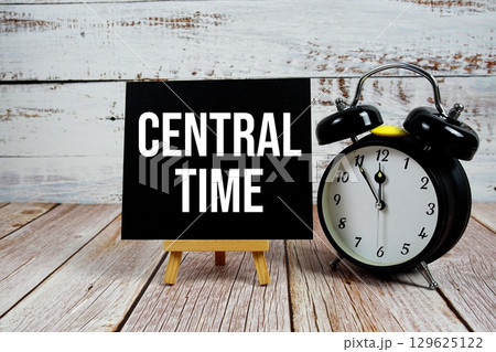 Central Time text with easel and alarm clock on wooden background Central Time text with easel and alarm clock on wooden background 129625122