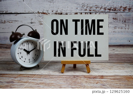 On Time In Full text with easel and alarm clock on wooden background On Time In Full text with easel and alarm clock on wooden background 129625160