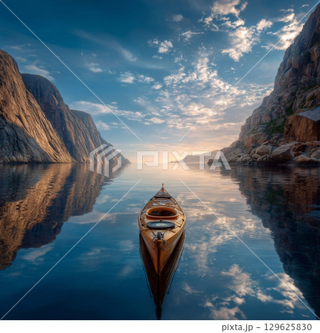 Kayak reflecting on calm water between cliffs at sunset in norway 129625830