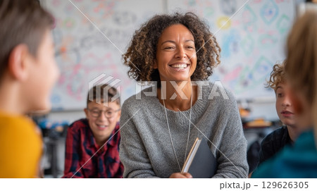 Smiling teacher interacting with cheerful students in classroom during math lesson 129626305