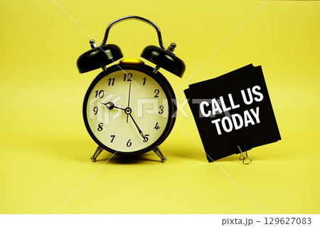 Call Us Today text message on sticky note with alarm clock on yellow background Call Us Today text message on sticky note with alarm clock on yellow background 129627083