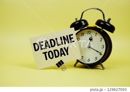 Deadline Today text message on paper card with alarm clock on yellow background Deadline Today text message on paper card with alarm clock on yellow background 129627093