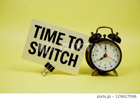 Time to Switch text message on paper card with alarm clock on yellow background 129627096