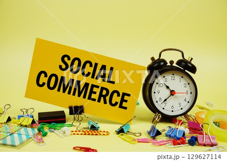 Social Commerce text on paper card with stationery and alarm clock on yellow background 129627114