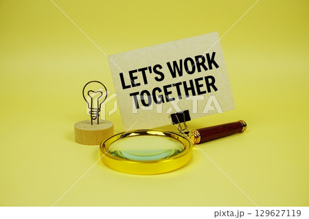 Let's Work Together text message on paper card with magnifying glass on yellow background 129627119
