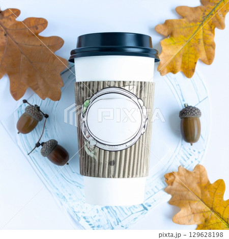 Coffee Cup Surrounded by Autumn Oak Leaves and Acorns on White Surface 129628198