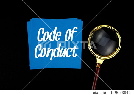 Code Of Conduct text on sticky note with magnifying glass on black background 129628840