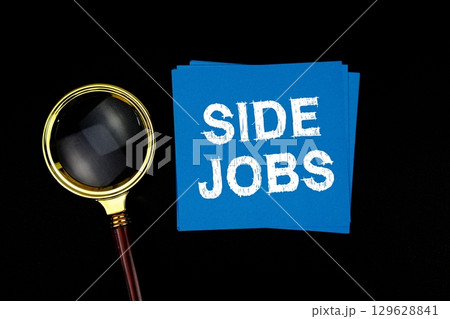 Side Jobs text on sticky note with magnifying glass on black background 129628841