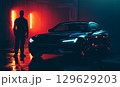 A police officer stands near patrol cars on a misty street at night, with blue and red lights reflecting on the wet road, creating a tense atmosphere of a potential crime scene 129629203