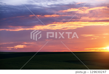 An incredible sunset over the field illuminates the cloudy sky. An incredible sunset over the field illuminates the cloudy sky. 129630247