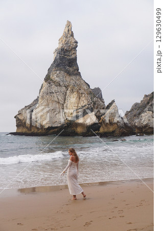 In Solitude by the Ocean A Woman Walking Alone Peacefully on the Beautiful Scenic Beachside 129630499