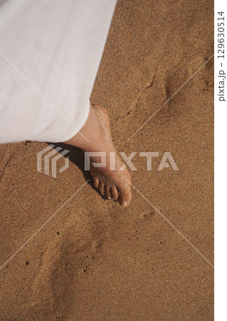 Experience the Peaceful Serenity of a Beautiful Beach with Barefoot Steps Enjoying the Sand 129630514