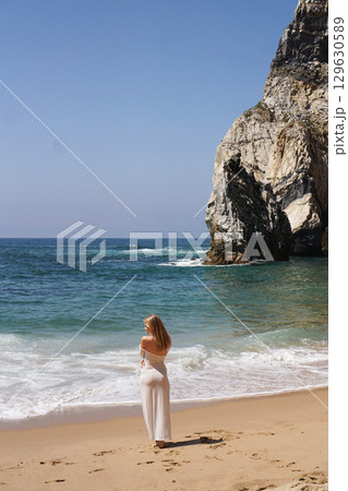 In Solitude by the Ocean A Woman Walking Alone Peacefully on the Beautiful Scenic Beachside 129630589