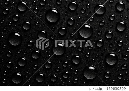 High-contrast macro image of water droplets on a black textured background creating a glossy reflective effect High-contrast macro image of water droplets on a black textured background creating a glossy reflective effect 129630899