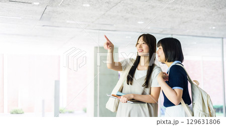 校内で指差し会話をする女子大生二人 校内で指差し会話をする女子大生二人 129631806
