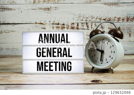 Annual General Meeting text on light box with alarm clock on wooden background Annual General Meeting text on light box with alarm clock on wooden background 129632098